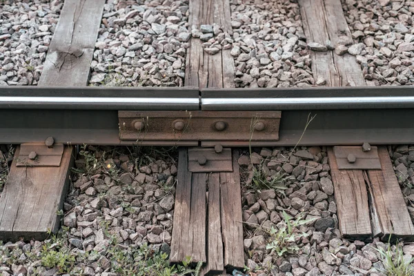 Tukang tidur lama, di kota ada jalur trem. Di alam, papan kayu basah. Penggandengan rel logam . — Stok Foto