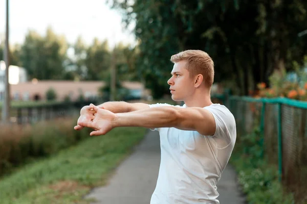 Männliche Athleten beim Aufwärmen in der Natur, auf der Straße in der Stadt, beim Aufwärmen der Muskeln der Hände. im Sommer im Park. Lebensstil. — Stockfoto