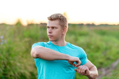 Bir erkek Koç bir ısınma eklem yapar. Parkta koşucu sabah. Park açık havada. Yaz yaşam tarzı, motivasyon kavramı.