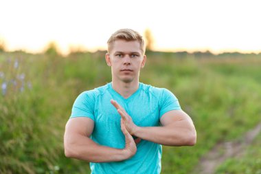 Genç adam koşucu sabah erken bir ısınma el yapıyor. Yaz yaşam tarzı, ısınma fikri. Park açık havada. Vücut ısınma, adam parkta kendine güvenen bir görüntüdür.