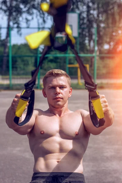 Un atleta masculino está ocupado bucles, flexiones en la valla. En verano, en pantalones cortos y una camiseta blanca. Vida sana de y —  Fotos de Stock