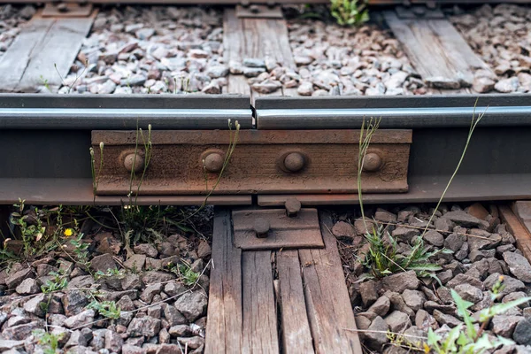 A close-up of rust metal rivets. Old sleepers, in city there is a tram line. In nature, a wet wooden board. Coupling of metal rails.