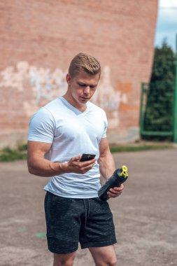 Bir erkek atlet açık havada spor için geçerlidir. Kaslı kolları. Sarışın beyaz bir tişört. Vücut yaşam tarzı