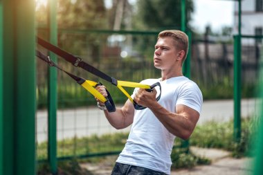 Bir erkek atlet açık havada spor için geçerlidir. Kaslı kolları. Sarışın beyaz bir tişört. Vücut yaşam tarzı