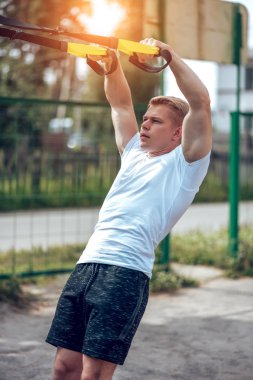 Bir erkek atlet açık havada spor için geçerlidir. Kaslı kolları. Sarışın beyaz bir tişört. Vücut yaşam tarzı