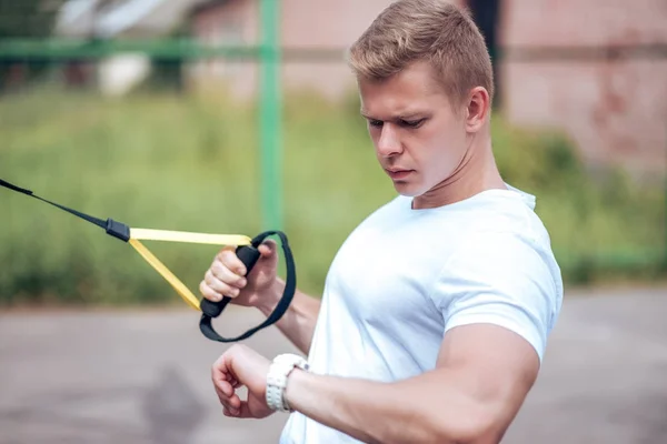 Ein männlicher Sportler treibt Sport an der frischen Luft. Muskulöse Arme. Blondine im weißen T-Shirt. Lebensstil des Bodybuilders — Stockfoto