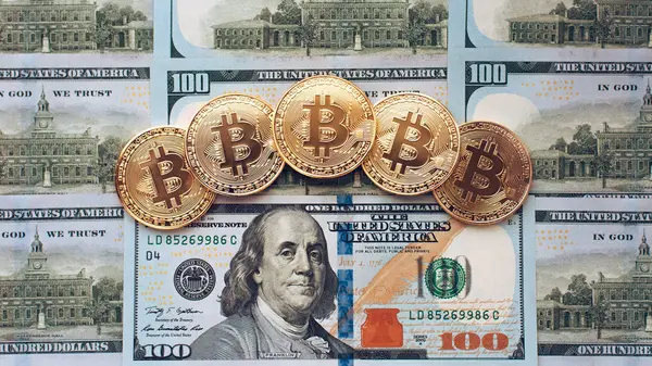 Monedas bitcoin, hay dinero, en la mesa un billete de 100 dólares. Los billetes se distribuyen sobre la mesa en un orden de 100 dólares. Las monedas de oro son criptomonedas . —  Fotos de Stock