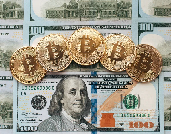 Monedas bitcoin, hay dinero, en la mesa un billete de 100 dólares. Los billetes se distribuyen sobre la mesa en un orden de 100 dólares. Las monedas de oro son criptomonedas . —  Fotos de Stock