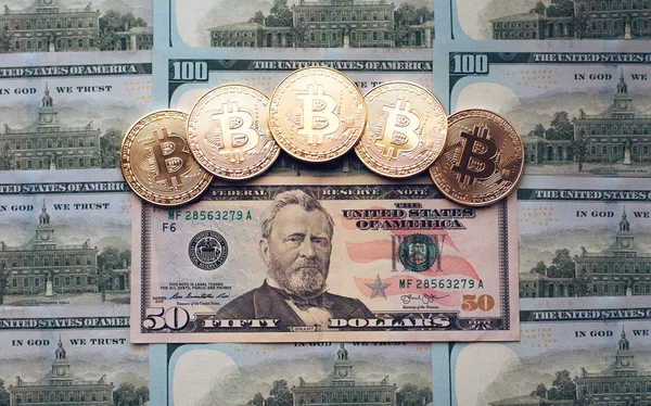 Monedas bitcoin, el dinero se encuentra, en la mesa de billetes de 50 dólares. Los billetes se distribuyen sobre la mesa en un orden gratuito de 50 dólares. Las monedas de oro son criptomonedas . —  Fotos de Stock