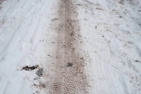 Грязные следы протектора на белой заснеженной дороге. Зимой следы снега из машины . — стоковое фото