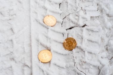Altın bitcoin Copprito sikkeleri üzerinde kar yalan söylüyorsun. Kimse gerekli. Kışın yolda araba izleri.