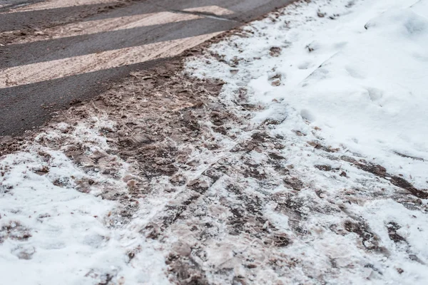 Зима в городе зебра пешеходного перехода. Грязные снежные следы авто колес, отпечатки ног пешеходов на грязном снегу зимой . — стоковое фото
