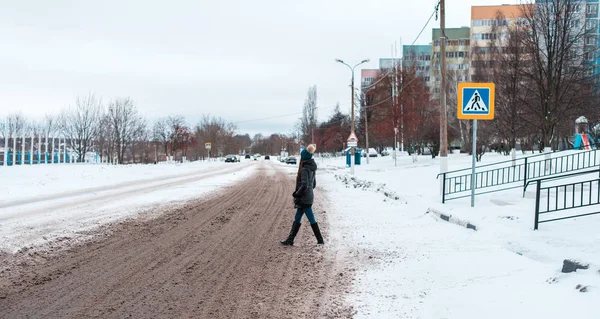 Pejalan kaki menyeberang jalan di musim dingin di kota di jalan tertutup salju, jejak roda pada salju di kota pada zebra . — Stok Foto
