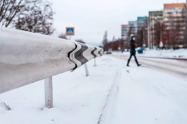Пешеход переходит дорогу зимой в городе по заснеженной дороге, следы колес на снегу в городе на зебре . — стоковое фото