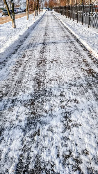 Close-up dari aspal di salju. Jalan-jalan di kota pada musim dingin, membersihkan salju membersihkan jalan dari salju di taman . — Stok Foto