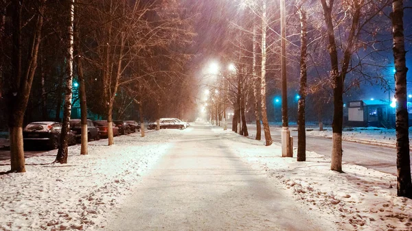 Зимой в городе, ночная улица с фонориями, сильный снежный ветер. В парке дорога покрыта снегом. Штормовой снег летит рядом с столбами ламп . — стоковое фото