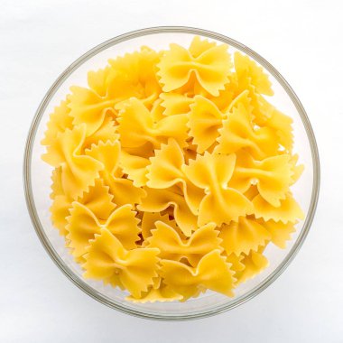 Farfalle makarna makarna beyaz izole arka planda Merkezi yakın çekim top ile cam kapta.