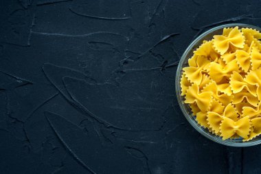 Farfalle makarna tarafından gelen siyah dokulu arka plan cam bardakta makarna. Top yakın çekim. Metin için ile yer.