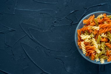 Çok renkli sarmal makarna tarafından gelen siyah dokulu arka plan cam bardakta makarna. Top yakın çekim. Metin için ile yer.