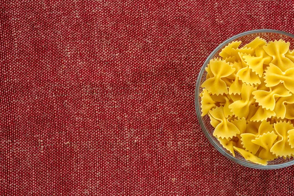 최고의 마 카로 니에서 센터 클로즈업에서 붉은 갈색 소박한 질감 배경에 유리 그릇에 farfalle 파스타. 텍스트를 위한 공간으로. — 스톡 사진