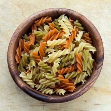 Çok renkli sarmal makarna makarna bir ahşap masa doku planda üst Merkezi yakın çekim üzerinde ahşap bir kasede.