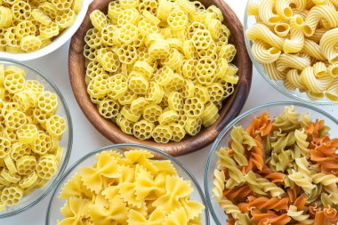 Makarna ruote bir cam ve ahşap kase ile beyaz bir arka plan üzerinde spiraller, yakından görmek farklı makarna üstten.