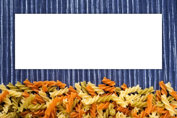 Macaronis spirale multicolore Belles pâtes décomposées avec un fond sur un fond rustique rayé bleu blanc texturé. Espace blanc pour le texte et les idées . — Photo