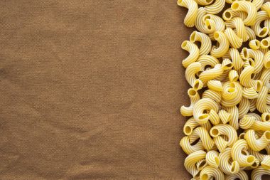 Sağda yan rustik kahverengi dokulu bir arka plan ile makarna makarna rigati güzel çürümüş. Üstten Görünüm yakın çekim. Metin için boş alan.