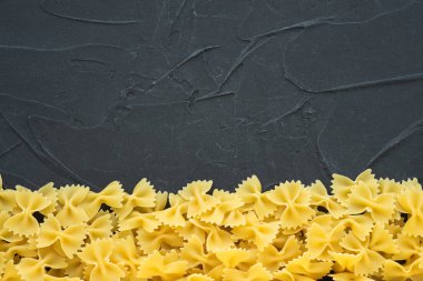 Farfalle makarna güzel bir altta siyah dokulu bir arka plan ile makarna çürümüş. Üstten Görünüm yakın çekim. Metin için boş alan.