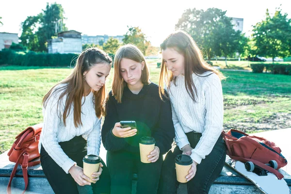 Tiga pacar perempuan gadis sekolah remaja 13-15 tahun, musim panas musim gugur hari di kota, membaca dan menonton pesan ponsel, menonton video Internet, aplikasi jejaring sosial. Dalam sweater rajutan . — Stok Foto