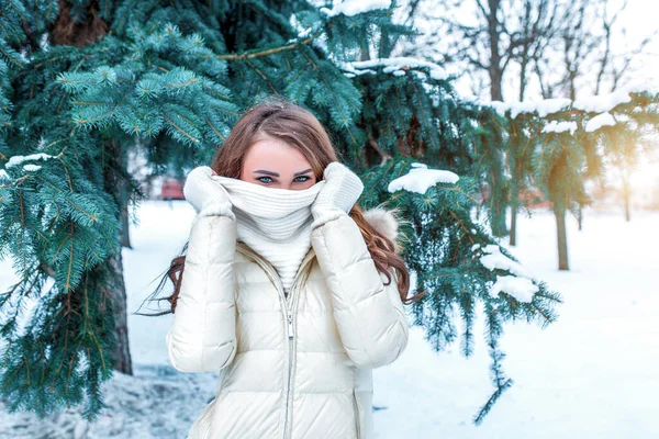 Belle femme hiver nature, couvre son visage avec une écharpe blanche, se réchauffe journée froide. Foulard blanc et veste chaude. Émotions confort plaisir détente hiver station parc. Espace libre pour le texte . — Photo