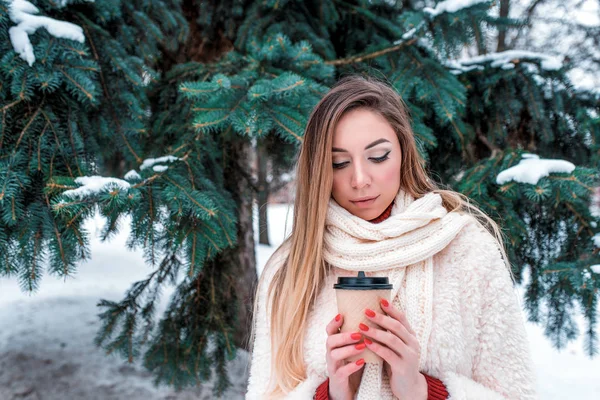 Wanita cantik di musim dingin di alam, memegang cangkir tangan teh kopi panas, menghangatkan pada hari yang dingin. Syal putih jaket hangat. Emosi kenyamanan relaksasi di resor musim dingin di taman . — Stok Foto