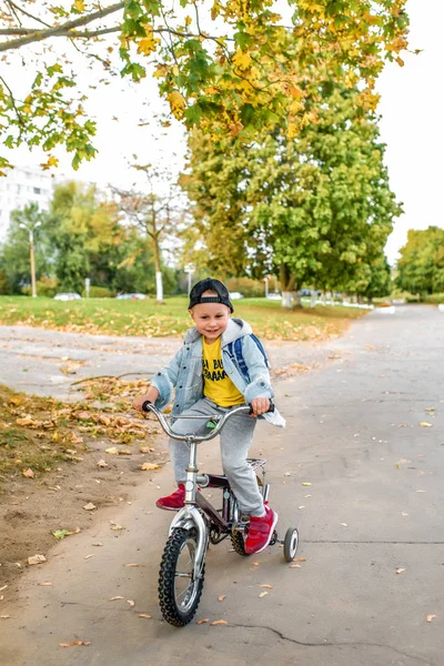 Anak laki-laki kecil yang bahagia berusia 3-5 tahun, di jalan di musim panas di kota, tersenyum kebahagiaannya, belajar mengendarai sepeda, belajar bagaimana untuk belajar. Pakaian musim gugur. Emosi kesenangan dan relaksasi . — Stok Foto