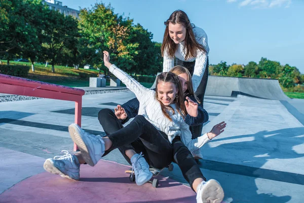 Tiga remaja remaja perempuan naik skateboard, senang bermain dan tertawa, olahraga musim panas tanah, di sweater hangat jatuh sore. Ruang kosong untuk menyalin teks. Emosi kebahagiaan menyenangkan . — Stok Foto