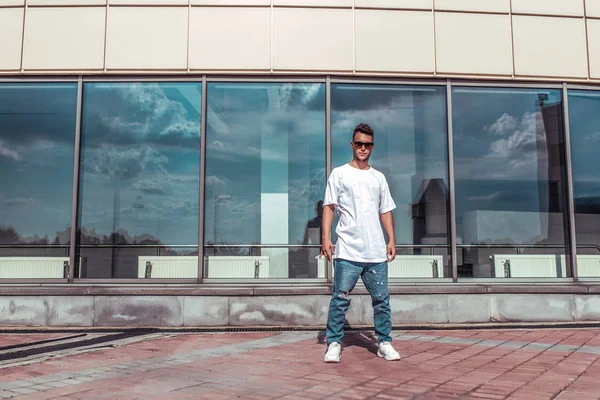 Male athlete standing windows, summer city, hip hop style, break dancer. Free space motivation text. Active lifestyle, modern fashionable hipster, street dancer. T-shirt sneakers jeans sunglasses.