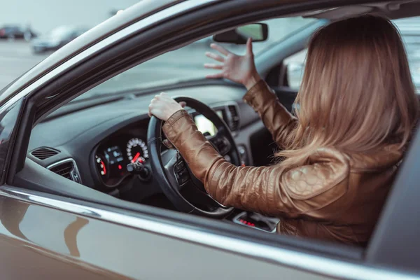 Egy nő autós dzsekit vezet, esküszik, hogy negatív baleseti stressz van az úton, parkolóház, ősszel város. Koncepció stressz negatív rossz hangulat, érzelmek meglepetés, baleset, konfliktus vezetés. — Stock Fotó