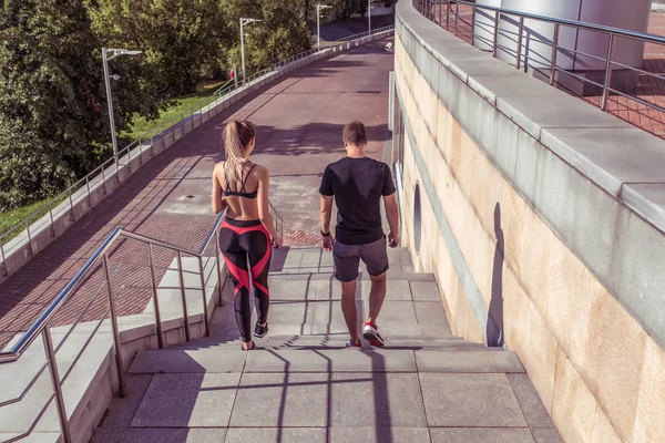 Молода спортивна пара чоловік жінка, гуляє по сходах, в літньому біговому місті, вид ззаду, спортивний одяг. Тренування з легкої атлетики, день-ранку. Активний спосіб життя фітнесу, вільна текстова мотивація . — стокове фото
