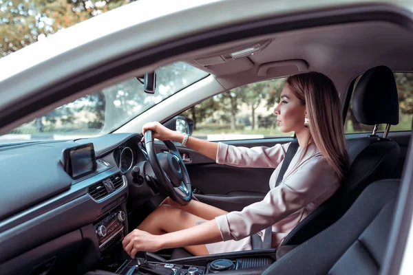 Bella donna d'affari ragazza, città estiva, cavalca interni auto. Pelle abbronzata, abito formale capelli lunghi trucco casual. Autonoleggio, car sharing. Guida a destra, guida a sinistra, cambio automatico . — Foto Stock