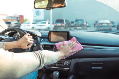 Yakın plan, el temizliği, araba temizliği, araba temizliği, alışveriş merkezinin yakınındaki otoparkta. Ekrana, direksiyona ve şanzımana dokun.