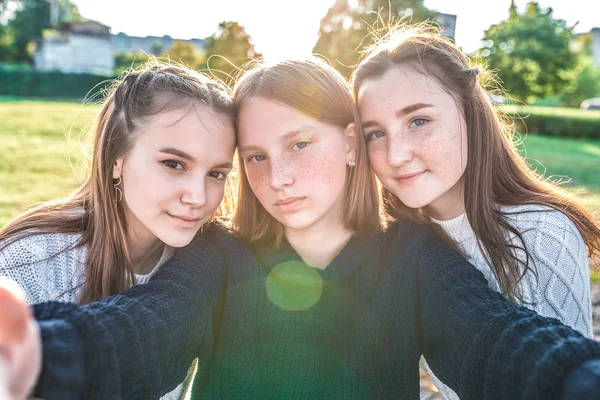 Tiga gadis sekolah remaja 13-15 tahun, musim gugur hari musim panas kota, mengambil foto selfie telepon. Emosi sukacita kesenangan kesenangan, tersenyum bahagia, pakaian santai, santai setelah sekolah pada liburan . — Stok Foto