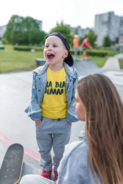 Familj mor kvinna liten pojke son 3-5 år gammal, sommar stad idrottsplan, skrikande, spela skrattande skridsko, känslor glädje, rolig avkoppling helgen. Vardagskläder, föräldrastöd för barn. — Stockfoto