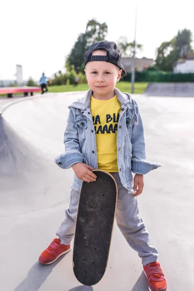 Liten pojke 3-5 år gammal, lära sig att rida skateboard, höst dag, casual varma kläder. Denim med en basebollkeps. Körlektioner, första erfarenhet, utomhussport. Posing i handskate. — Stockfoto