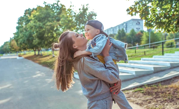Mutlu aile kadını anne ve küçük oğlan çocuğu, oynayın ve eğlenin, sonbahar günü şehir parkında. Eğlenceli rahatlama haftasonunun heyecanı. Sıcak giyimli kotlu tişört. Ailede sevgiyi önemseyen. — Stok fotoğraf