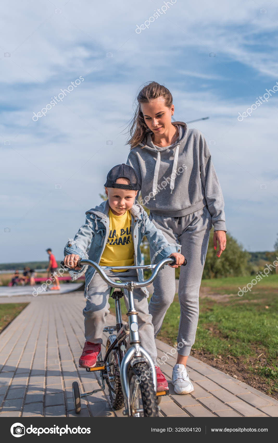 Женщина мама поддерживает и помогает ребенку на велосипеде