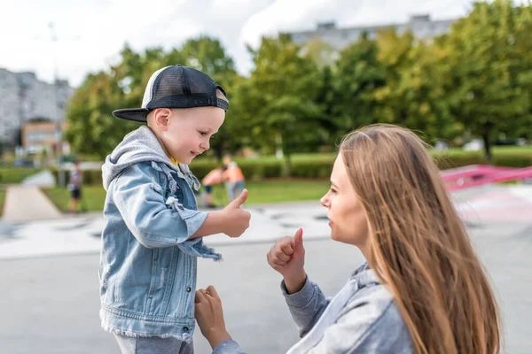 Ibu dan anak yang bahagia, bermain tertawa dan tersenyum, pada musim gugur di taman musim panas, memakai jins dan topi bisbol, merawat dan mendukung pelatihan akhir pekan. Istirahat dengan orang tua di alam . — Stok Foto