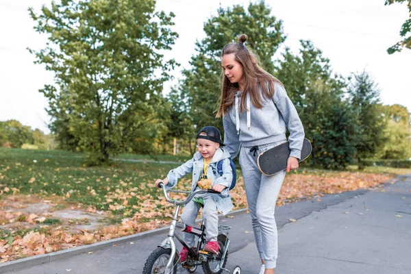 Ibu mengajarkan anak laki-laki untuk naik sepeda, mendukung perawatan dan pelatihan, anak kecil berusia 3-5 tahun, musim panas di kota, musim gugur, emosi cinta, perawatan, relaksasi dan berjalan. Liburan akhir pekan dengan orang tua . — Stok Foto
