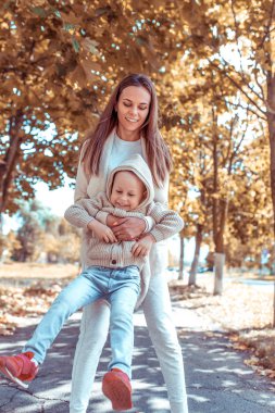 Küçük oğlan, anne kadını oynuyor, şefkatli ve ilgili çocuğu oynuyor, sonbahar günü sokakta kalın giysiler içinde, yaz doğada. Mutlu ol, rahatla, neşelen, aşk duyguları. Hafta sonu ebeveynlik kavramı.