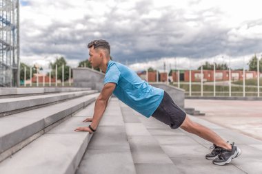Genç sporcu, erkek sporcu, şınav çeken ve barlarda duran, yaz günü spor salonu spor salonu, modern gençliğin aktif yaşam tarzı, spor giyim şortu spor ayakkabıları. Yaşam motivasyonu.