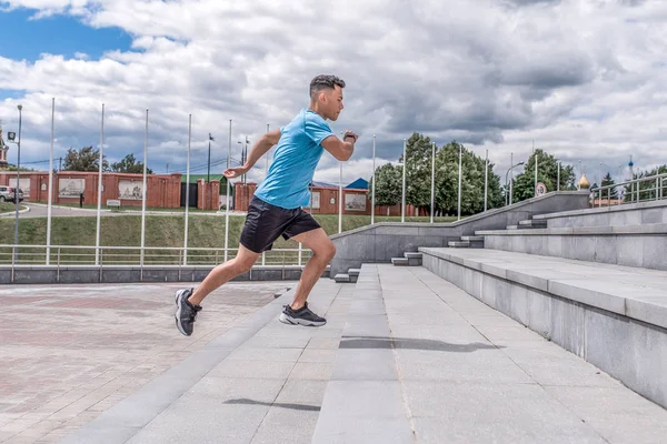 Young sportsman, male athlete, runs up steps, summer day city, workout fitness, active lifestyle of modern youth, sportswear t-shirt shorts sneakers. Motivation for life. Free space and copy text. — ストック写真