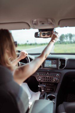 Arabadaki kadın, ayar ve dikiz aynası, arabada sürüş güvenliği, park ve arka trafik. Arabayı ters park et. Arka koltuğa bakıyor, yolcuları ve küçük çocukları kontrol ediyor..